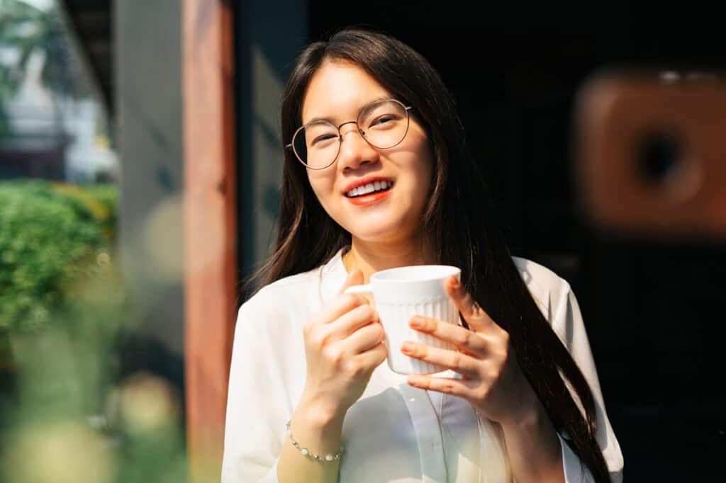 a woman with glasses holding a cup of coffee