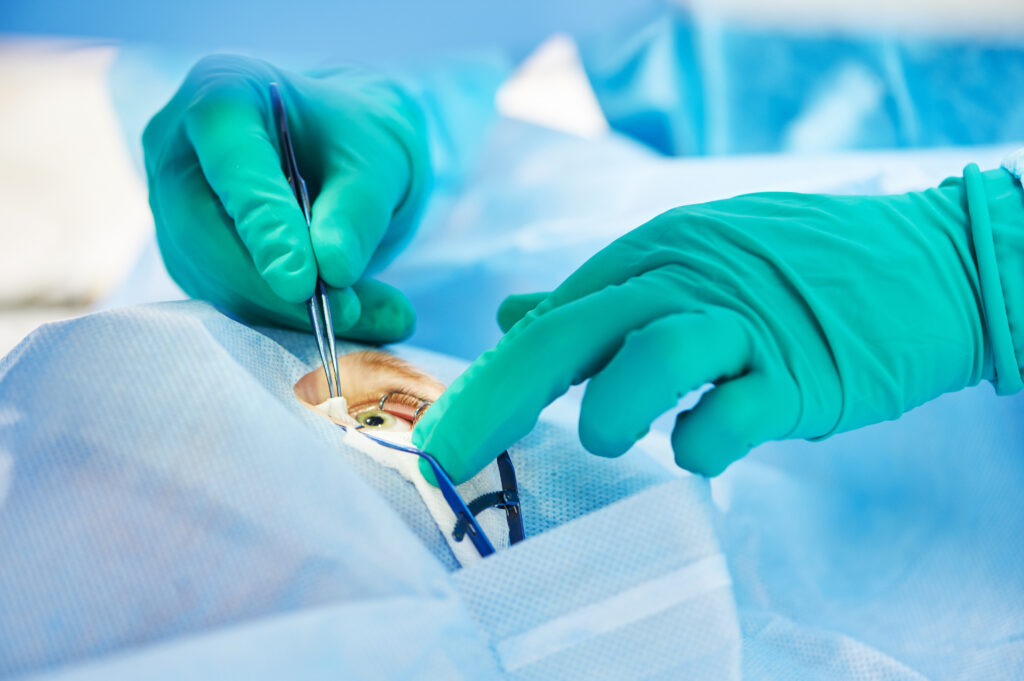 surgeon's hands in gloves performing laser eye vision correction correction